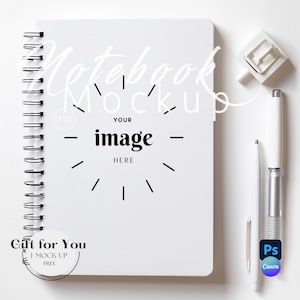 May include: White spiral bound notebook mockup with the text "Notebook Mockup" and "Your image here" on the cover. The notebook is on a white surface with a white pen and a white paperclip.
