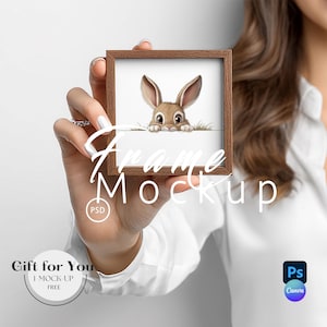 Puede incluir: Una impresión cuadrada con marco marrón que presenta un conejito de dibujos animados asomándose por encima de una superficie blanca. Las palabras "Frame Mockup" están superpuestas en la imagen. La imagen también incluye el texto "Gift for You" y "I Mock-Up Free".