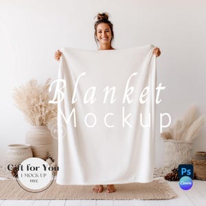 May include: A woman displays a white blanket mockup, with the words "Blanket Mockup" in a script font. The background features decorative vases, pampas grass, and a woven rug. The image also includes the text "Gift for You 1 Mock-up Free".