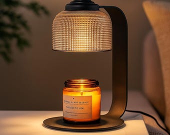 May include: A black metal candle warmer lamp with a textured glass shade and a round base. A lit candle in a glass jar sits on the base. The candle label reads "YOMEAL PLANT ESSENCE PASSAGE TO HEAL".