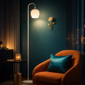 May include: A modern living room scene featuring a white floor lamp with a curved arm and a frosted glass shade. An orange armchair with a teal cushion sits beside the lamp. A decorative rose and a candle holder are also visible.