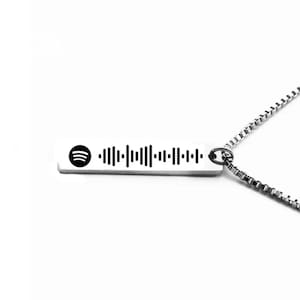 Puede incluir: Un collar de cadena de plata con un colgante rectangular que presenta un logotipo de Spotify y un código de barras.