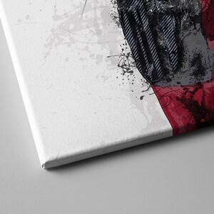 May include: A close-up of a canvas print with a red, black, and white abstract design. The design features a splatter effect and a geometric pattern.