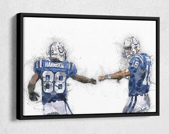 May include: Framed artwork depicting two American football players in blue and white uniforms. One player's jersey displays the number 88 and the name "Harrison". They are fist-bumping, set against a white backdrop with artistic paint splatter effects.