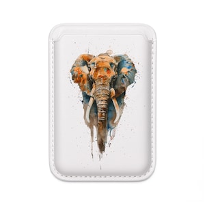 Puede incluir: Funda de teléfono blanca con una pintura de acuarela de un elefante. El elefante está representado con tonos naranja, azul y marrón, con salpicaduras de pintura alrededor de la imagen. La funda tiene un borde cosido.