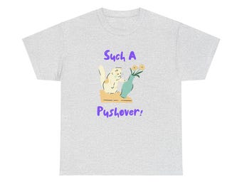 Puede incluir: Una camiseta gris claro con un gato de dibujos animados y flores en un jarrón. El texto "Such a Pushover!" está impreso en morado en la camiseta.