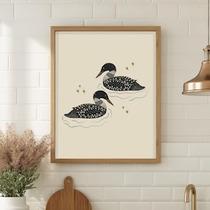 Puede incluir: Una impresi&oacute;n art&iacute;stica enmarcada con dos somorgujos flotando en el agua. Los somorgujos tienen cuerpos con patrones en blanco y negro, cabezas negras y picos largos y puntiagudos. El fondo es de color beige claro, con peque&ntilde;os acentos de estrellas doradas.