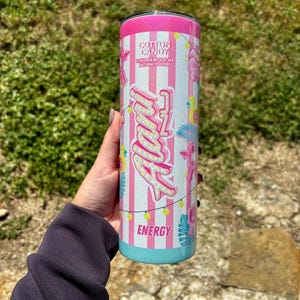 K&ouml;nnte beinhalten: Ein rosa-wei&szlig; gestreifter Becher mit dem Wort "Angel" in einer Schriftart im Leuchtstil. Der Becher hat einen rosa Deckel und einen t&uuml;rkisfarbenen Boden. Der Text "Cotton Candy" und "Energy" sind ebenfalls sichtbar.