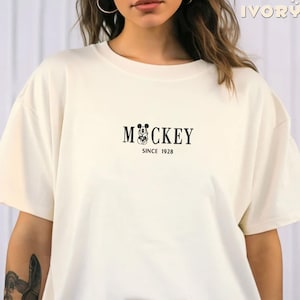 May include: A white t-shirt with a black Mickey Mouse graphic and the text "Mickey Since 1928".