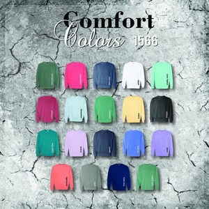 Pode incluir: Uma exibi&ccedil;&atilde;o de camisolas de v&aacute;rias cores, incluindo verde, rosa, azul e branco. Cada camisola &eacute; rotulada com um nome de cor, como "blue jean" e "chalky mint". O texto "Comfort Colors 1566" est&aacute; no topo.