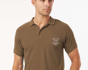 May include: A brown polo shirt with short sleeves and a collar. The shirt features a white outline drawing of a dog with the name "Alfie" underneath. The shirt is made of a soft material.