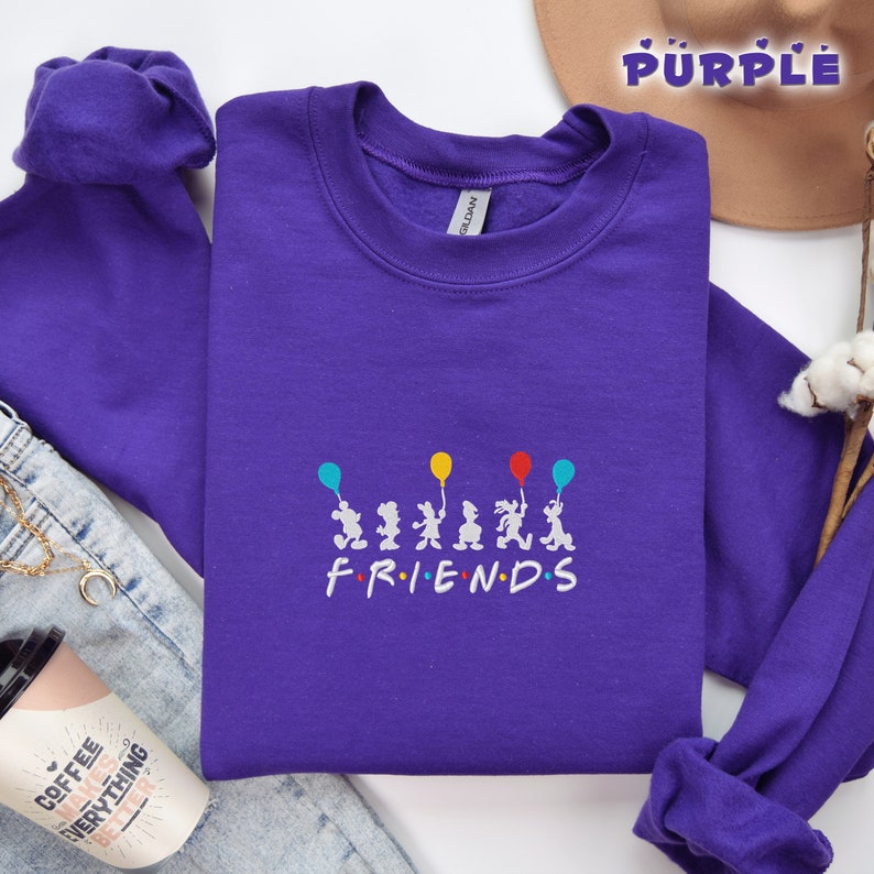 May include: Purple sweatshirt with a white graphic of six cartoon characters holding balloons and the word "FRIENDS" underneath.