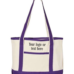 May include: Cream-coloured tote bag with purple accents. The bag has a purple base, trim, and handles. A front pocket displays the text "Your logo or text here". This durable tote is ideal for carrying various items.