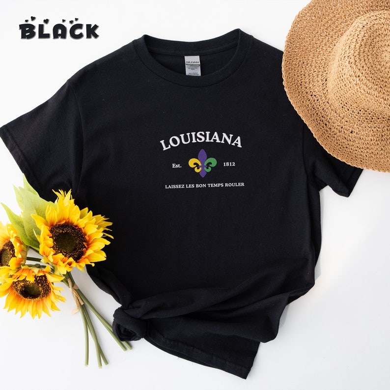 May include: Black t-shirt with a white graphic design featuring the text "LOUISIANA" with a fleur-de-lis symbol and the text "Est. 1812" and "LAISSEZ LES BON TEMPS ROULER".