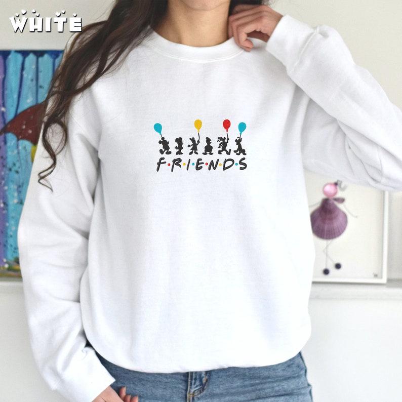 May include: White sweatshirt with a graphic of six cartoon figures holding balloons and the text "FRIENDS" underneath.