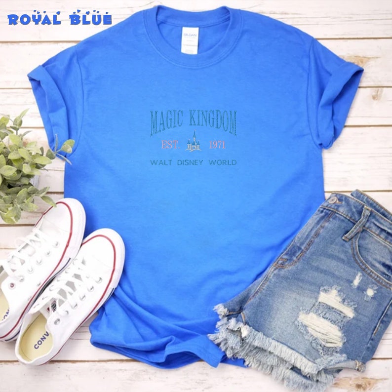 May include: A royal blue t-shirt with the text "Magic Kingdom Est. 1971 Walt Disney World" and a graphic of Cinderella's castle.