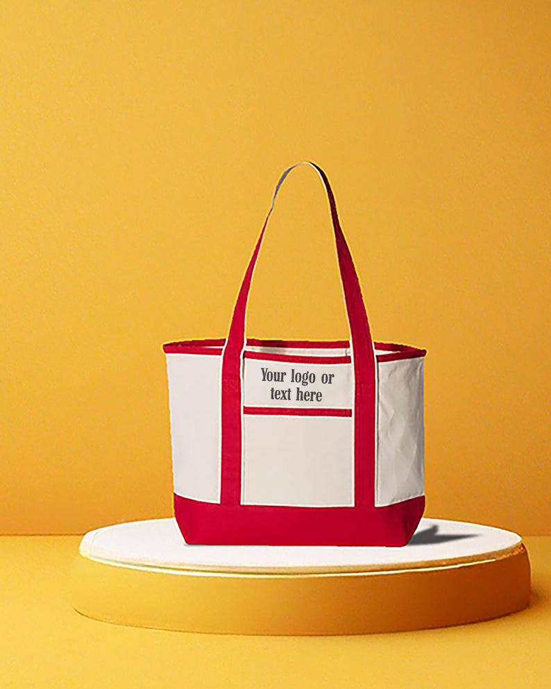 May include: A white and red tote bag with red handles and trim. The bag has a rectangular pocket with the text "Your logo or text here". The bag is on a white platform with a yellow background.