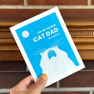 Close up of funny greeting card of illustrated cat meowing loudly with a clock showing 5am.

Message: You're the best cat dad. Now feed me.