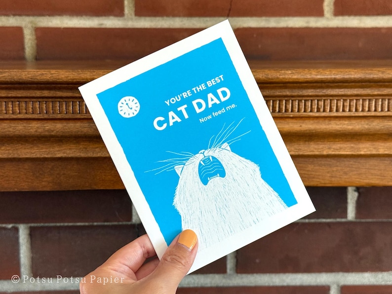 Close up of funny greeting card of illustrated cat meowing loudly with a clock showing 5am.

Message: You're the best cat dad. Now feed me.