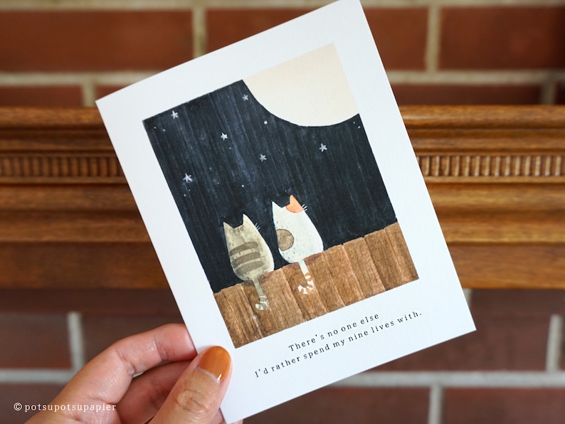 Close up of greeting card with hand painted illustration of two cats sitting on a fence and looking up at the moon.

Message: There's no one else I'd rather spend my nine lives with.