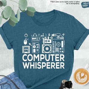 May include: A teal blue t-shirt with a white design of computer parts and the text "COMPUTER WHISPERER".