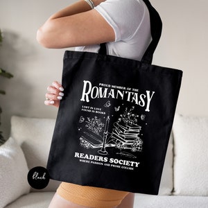 a woman holding a black tote bag with a picture of a book