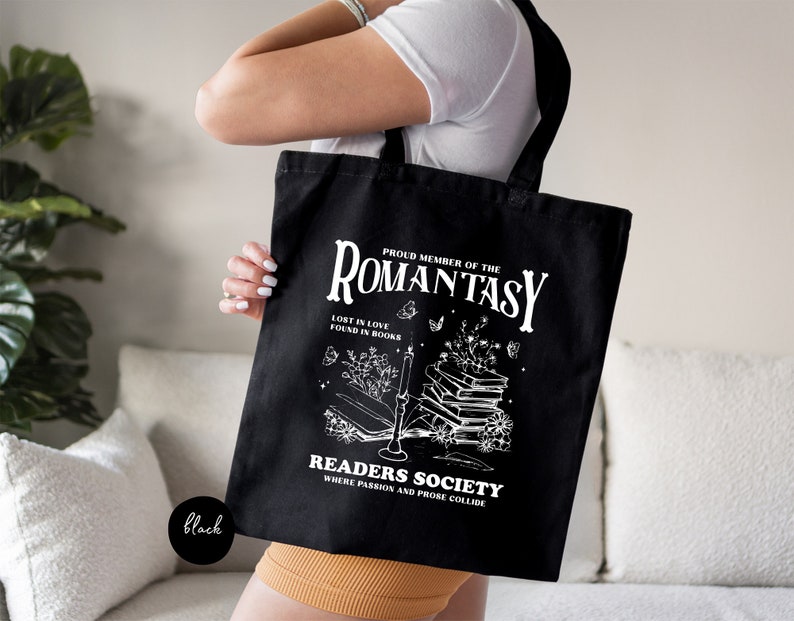 a woman holding a black tote bag with a picture of a book