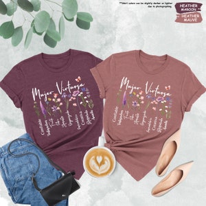 a couple of t - shirts sitting next to a cup of coffee