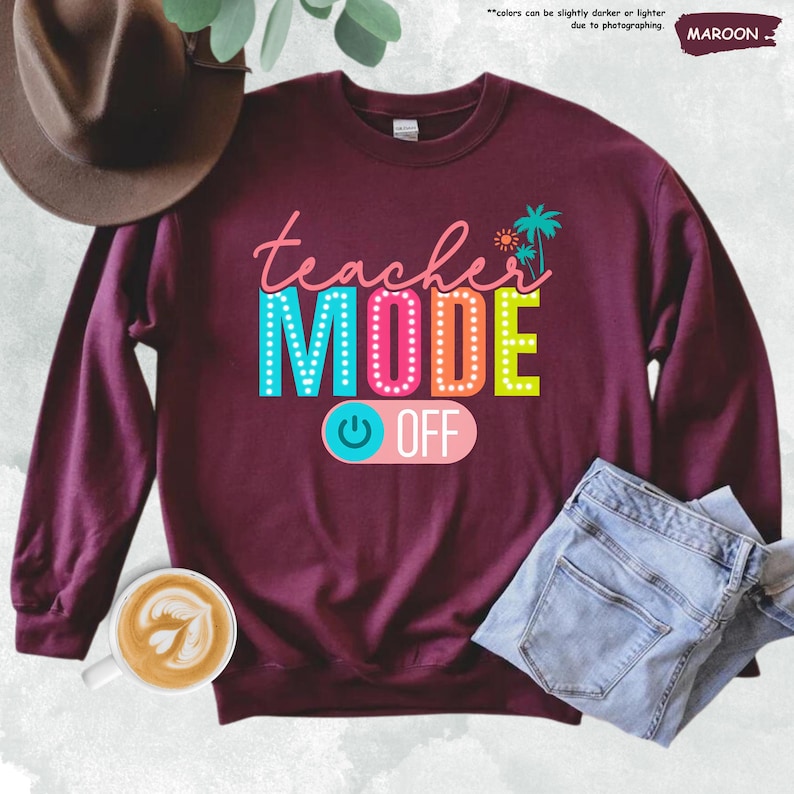 May include: A maroon sweatshirt with the text "teacher MODE OFF" in colorful letters with a light blue power button graphic. The text is in a retro style with light bulbs around the letters.