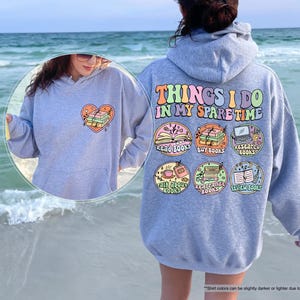 a woman standing on a beach wearing a hoodie