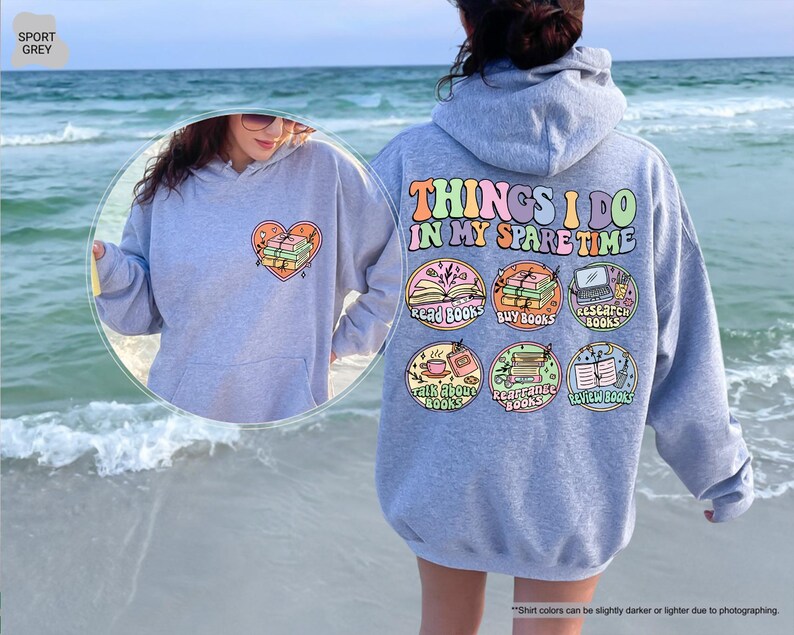 a woman standing on a beach wearing a hoodie