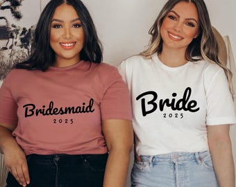 May include: Two women wearing matching t-shirts. One shirt says "Bride 2025" in black script and the other says "Bridesmaid 2025" in black script.