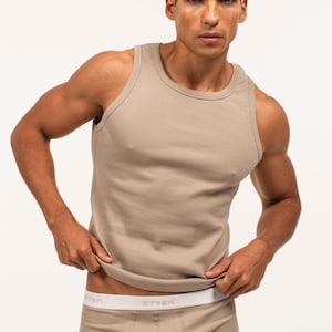May include: A beige ribbed tank top with a white waistband. The waistband has the word "STTEN" printed on it.