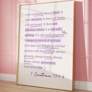 May include: Framed print with a gold border, featuring the text "Love is patient, love is kind" from 1 Corinthians 13:4-8. The text is in a handwritten style, with certain words highlighted in a purple hue. The background is a soft white.
