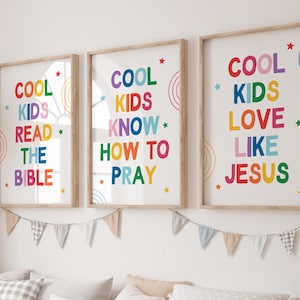 Puede incluir: Tres impresiones enmarcadas con las frases "COOL KIDS READ THE BIBLE", "COOL KIDS KNOW HOW TO PRAY" y "COOL KIDS LOVE LIKE JESUS" en texto colorido. Cada impresión tiene un marco de madera y detalles de estrellas y arcoíris.