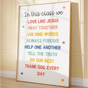 May include: A framed print with the text "In this class we" followed by a list of positive affirmations in various colors. The print is in a light wood frame and has colorful star accents.