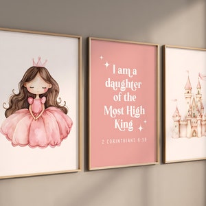 Puede incluir: Tres impresiones enmarcadas con fondo rosa. La impresión de la izquierda presenta una ilustración de acuarela de una princesa con una corona y un vestido rosa. La impresión del medio tiene el texto "Soy una hija del Rey Altísimo" con la referencia bíblica "2 Corintios 6:18". La impresión de la derecha muestra una ilustración de acuarela de un castillo rosa.