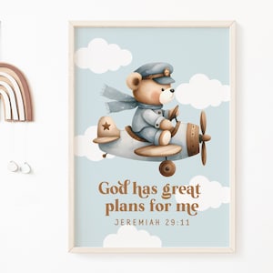 Puede incluir: Una impresión ilustrada azul y marrón de un oso de peluche con un gorro de piloto y volando un avión con el texto "Dios tiene grandes planes para mí" y "Jeremías 29:11" debajo de la imagen.