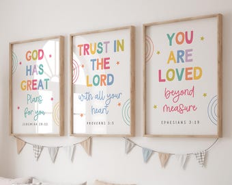 May include: Three framed wall art prints with light wood frames. Each print features colorful text and small star and circle graphics. The text reads: GOD HAS GREAT Plans for you JEREMIAH 29:11, TRUST IN THE LORD with all your heart PROVERBS 3:5, and YOU ARE LOVED beyond measure EPHESIANS 3:19.