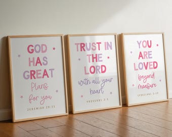 May include: Three framed art prints with inspirational quotes in pink and purple lettering. The prints read "GOD HAS GREAT Plans for you", "TRUST IN THE LORD with all your heart", and "YOU ARE LOVED beyond measure". Each print has a wooden frame.