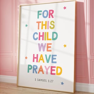 Può includere: Una stampa incorniciata colorata con il testo "FOR THIS CHILD WE HAVE PRAYED" in colori arcobaleno con stelle e il testo "1 SAMUEL 1:27" in basso.