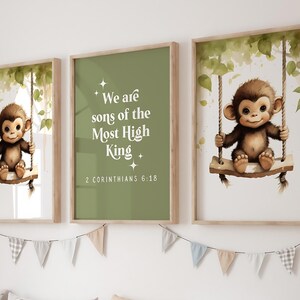 May include: Three framed prints with a jungle theme. The centre print features a green background with white text that reads "We are sons of the Most High King" and "2 Corinthians 6:18". The prints on either side feature a brown monkey sitting on a swing in a jungle setting.