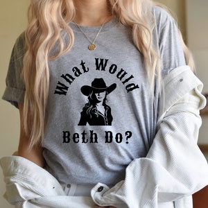 May include: Gray t-shirt with a black graphic of a woman wearing a cowboy hat and the text "What Would Beth Do?"