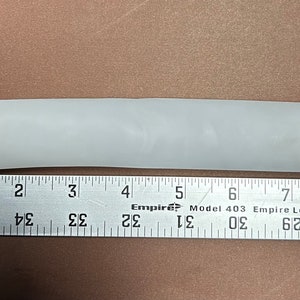 May include: A white, flexible, plastic tube measuring approximately 8 inches in length.