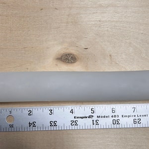 May include: A white plastic pipe measuring approximately 8 inches in length.