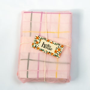 Napkin set wrapped up with pink tissue paper and hellomaë branded tag.