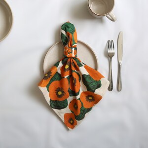 42 cm x 42 cm square napkin with large wonky nasturtium design print on off white base colour, 94%cotton/6% linen textured fabric with its matching ceramic nasturtium napkin ring.