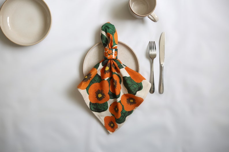 42 cm x 42 cm square napkin with large wonky nasturtium design print on off white base colour, 94%cotton/6% linen textured fabric with its matching ceramic nasturtium napkin ring.