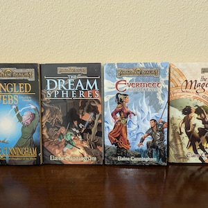 Può includere: Quattro libri di fantasy in brossura con copertine colorate che mostrano illustrazioni di personaggi e scene. I titoli sono "Tangled Webs", "Dream Spheres", "Evermeet Island of Elves" e "The Magehound Counselors & Kings Book 1".