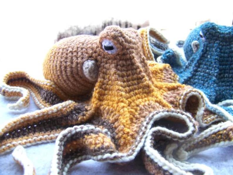 May include: A crocheted octopus plush toy with brown, yellow, and white yarn. The octopus has eight tentacles and a large head with large eyes.
